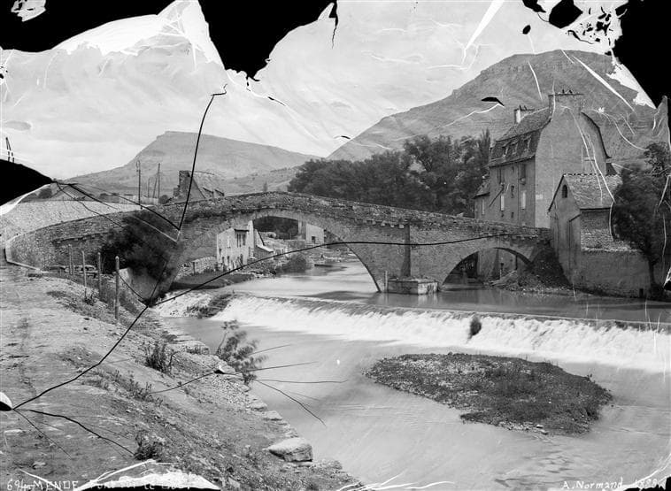 A torn, scratched 1888 photograph of a stone bridge
